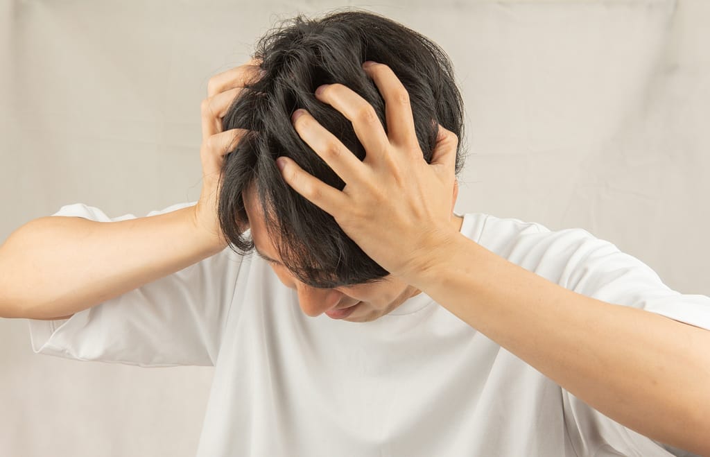 マッチングアプリで2回目に繋がらず、両手で頭を抱えて絶望している男性。