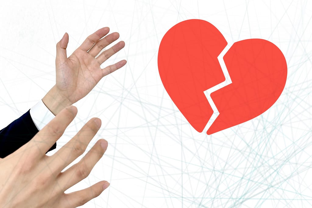 割れた赤いハートに手を伸ばす様子。マッチングアプリでの失恋や未練、追いかけてしまう気持ちを表現したイメージ画像。