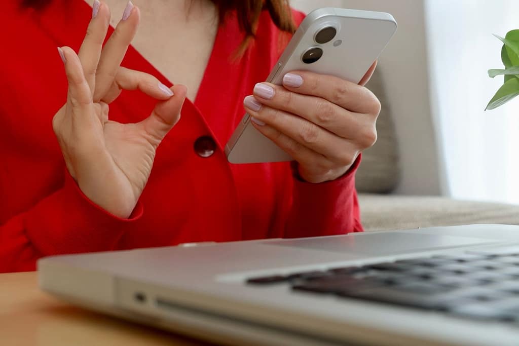 スマホを操作しながらOKサインを出す女性。マッチングアプリの追いメッセージを送る最適なタイミングをイメージした画像。